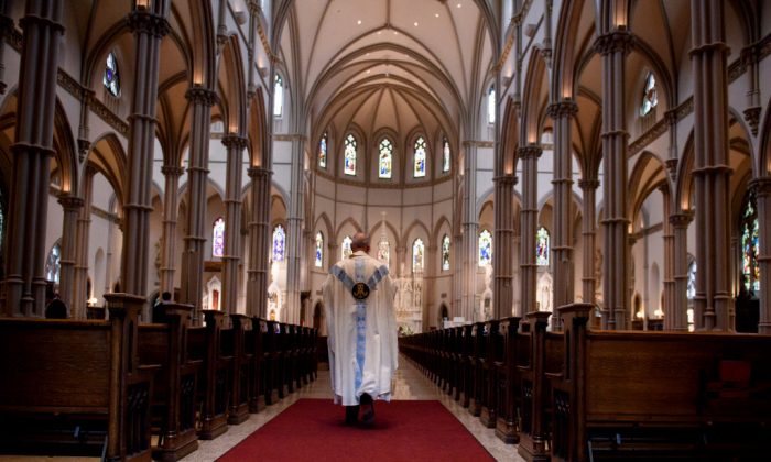 A priest walks to the sanctuary following a mass Photo by Jeff Swensen/Getty Images